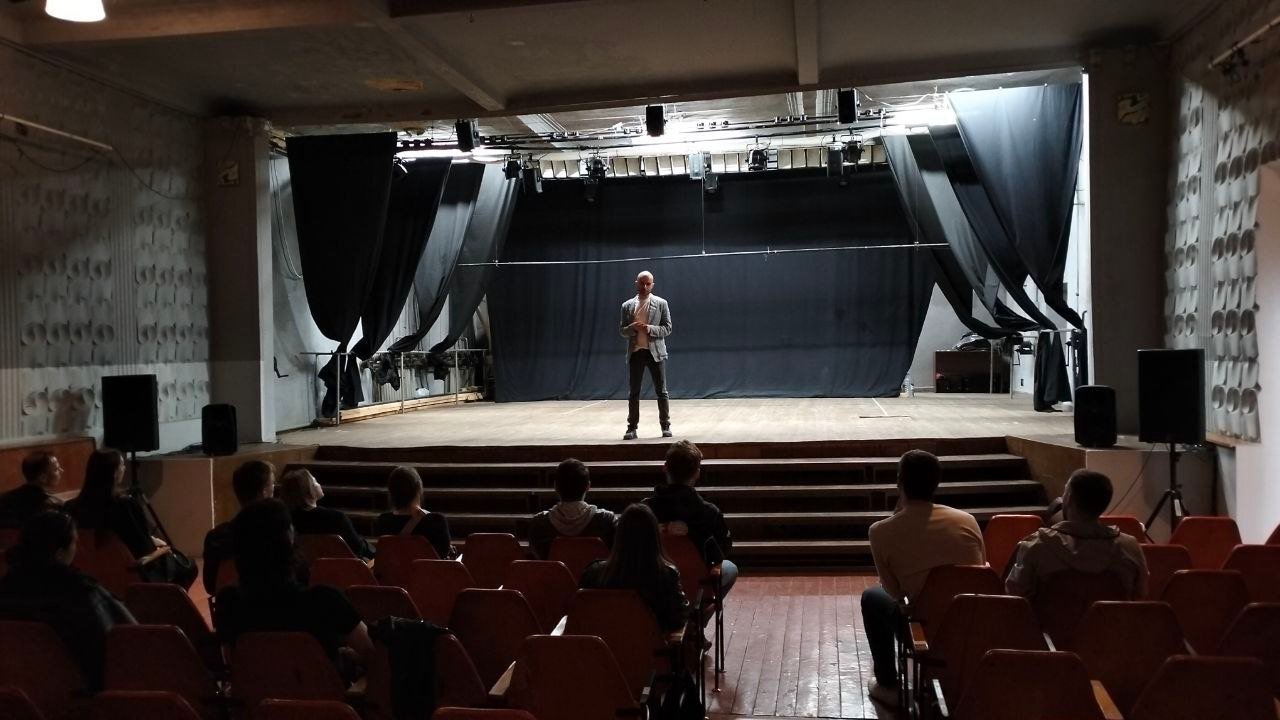 Un participant lucrează în centrul sălii, în timp ce grupul observă.